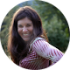 woman with long brown hair smiling in front of a green background
